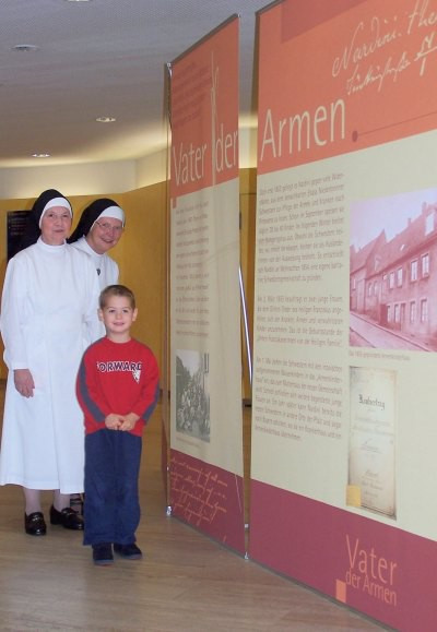 Schwester Fakunda und Schwester Oberin Hildebranda (Mitte) freuen sich über einen ganz jungen Besucher der Ausstellung